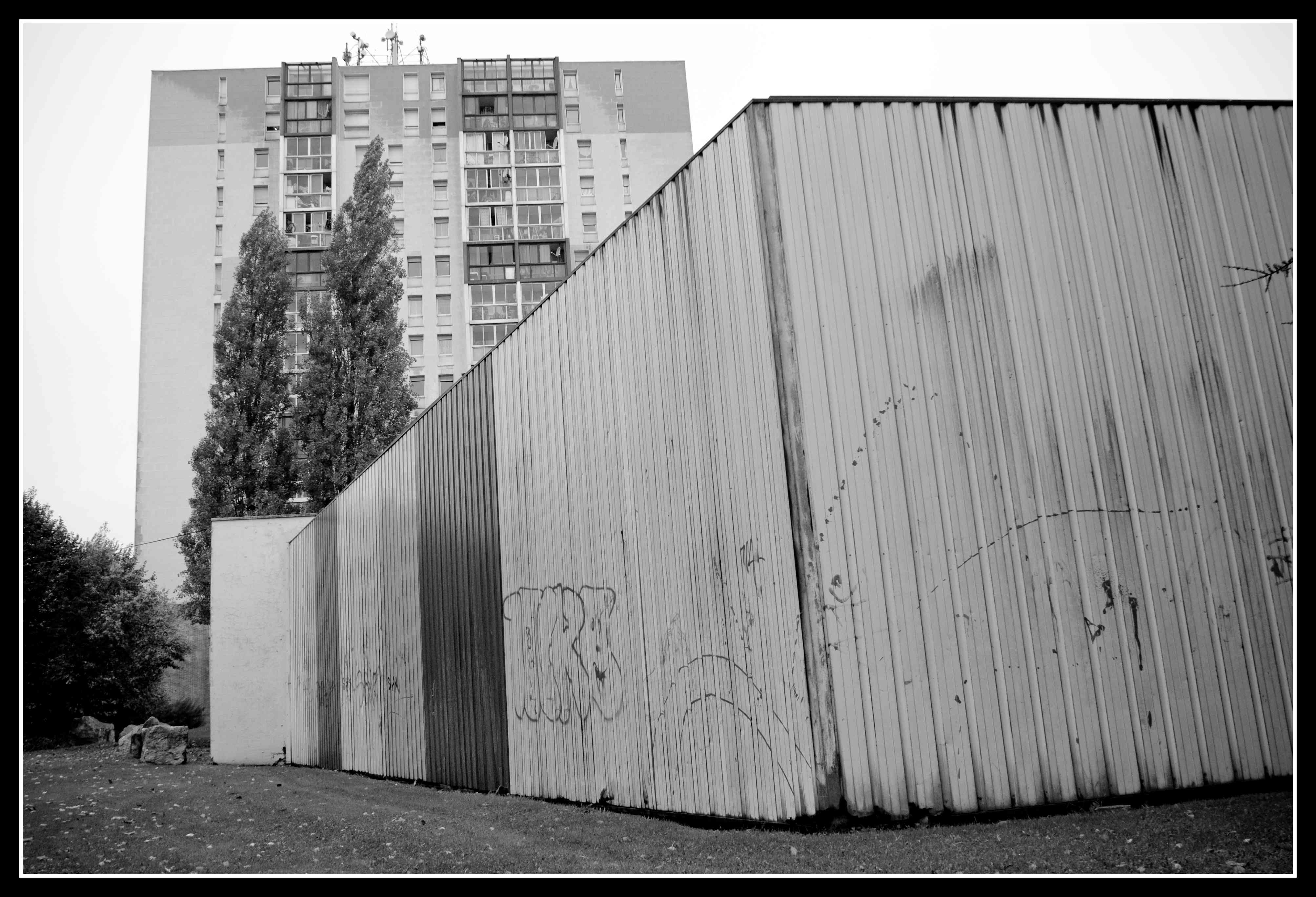Un entrepôt au milieu des tours. Seule l'enseigne PACTE - Carrefour à l'entrée nous signifie que le local n'est pas abandonné. Un entrepôt au milieu des tours. Seule l'enseigne PACTE - Carrefour à l'entrée nous signifie que le local n'est pas abandonné.